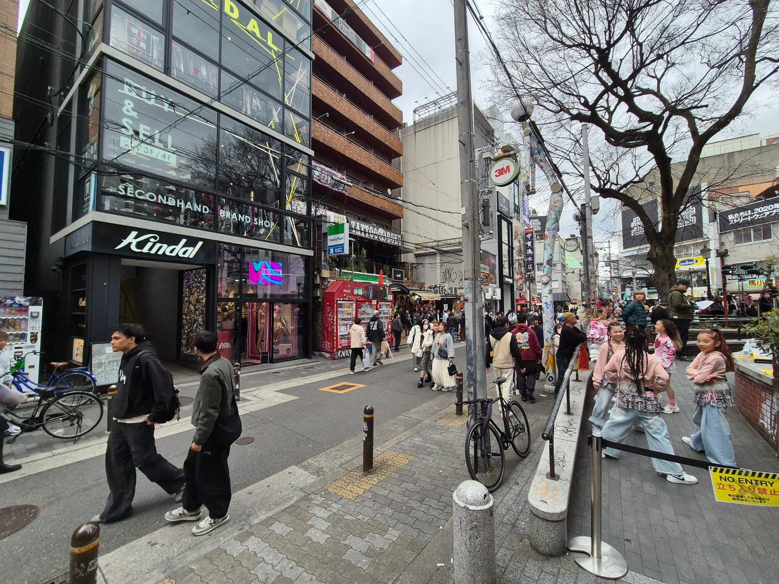 Una calle de Amerikamura en Osaka con tiendas de ropa de segunda mano, grafitis y jóvenes locales caminando entre bicicletas estacionadas