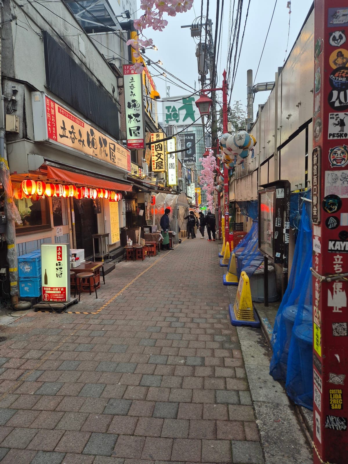 Callejón angosto de Omoide Yokochō al atardecer, con faroles rojos encendidos frente a pequeños restaurantes