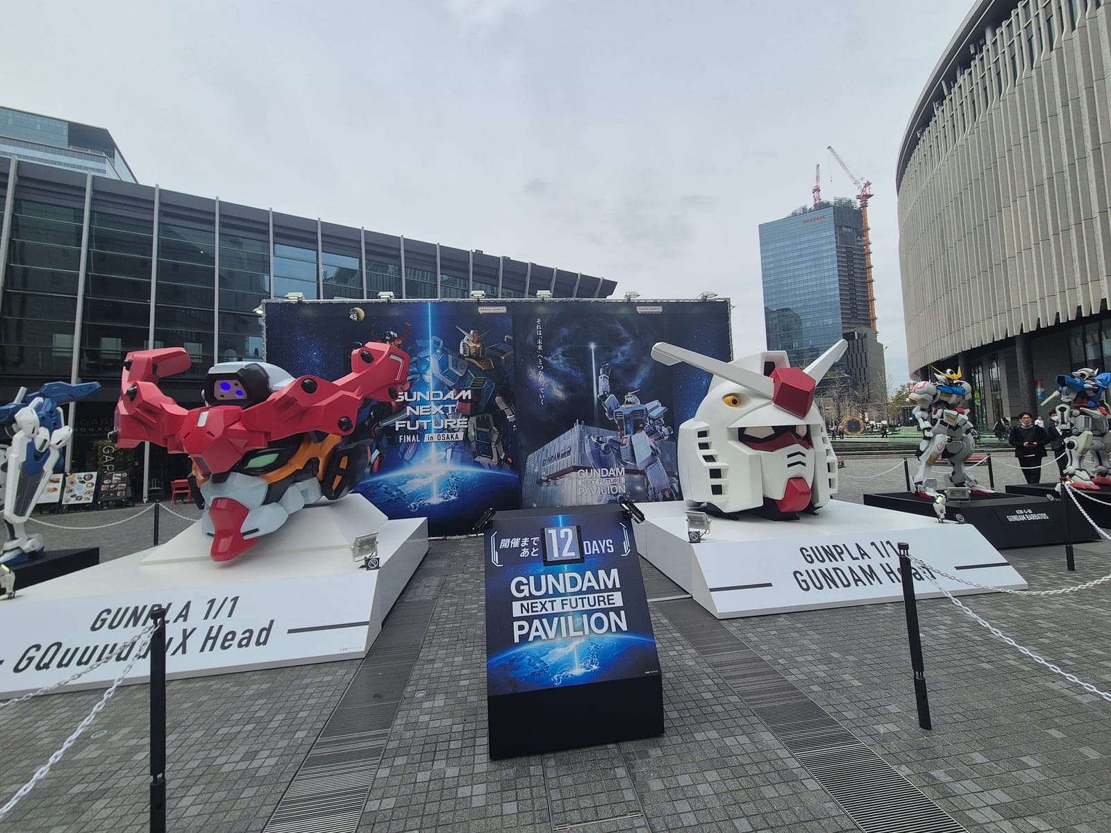 Explanada con varias figuras de Gundam a tamaño real y una pantalla anunciando el Gundam Next Future Pavilion en la plaza de Umekita, Osaka