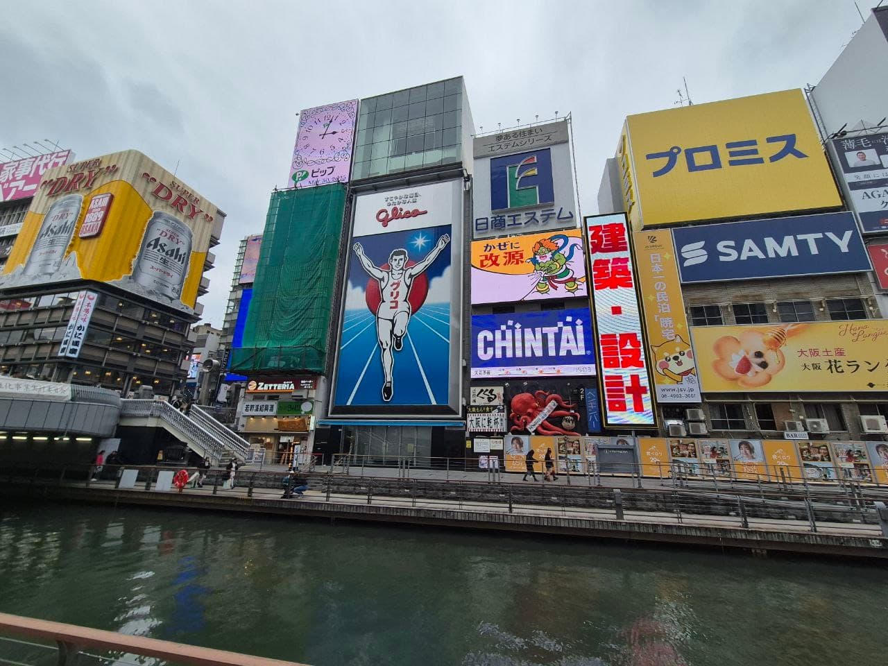 El letrero del corredor de Glico sobre el canal Dotonbori en Osaka, rodeado de otros anuncios luminosos como Chintai y Kirin, con el canal al frente