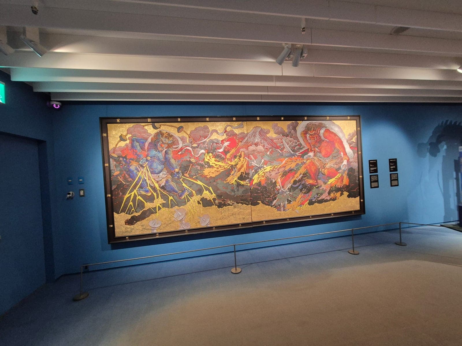 Mural de gran formato en el museo Koji Kinutani que representa a los dioses Raijin y Fujin, del trueno y el viento, sobre un fondo dorado con un volcán