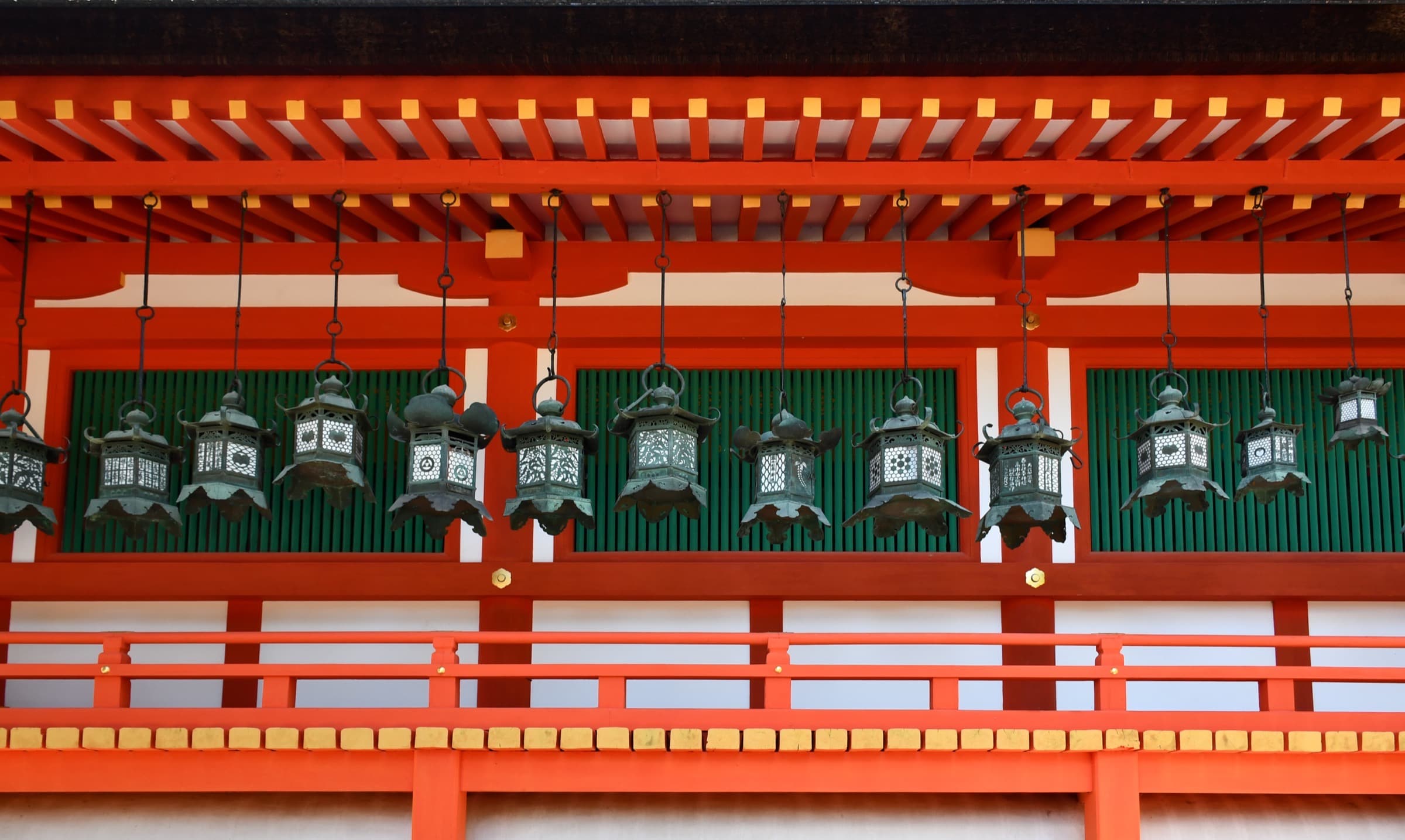 Una hilera de linternas de bronce colgando del techo de un corredor bermellón en el santuario Kasuga Taisha, en Nara