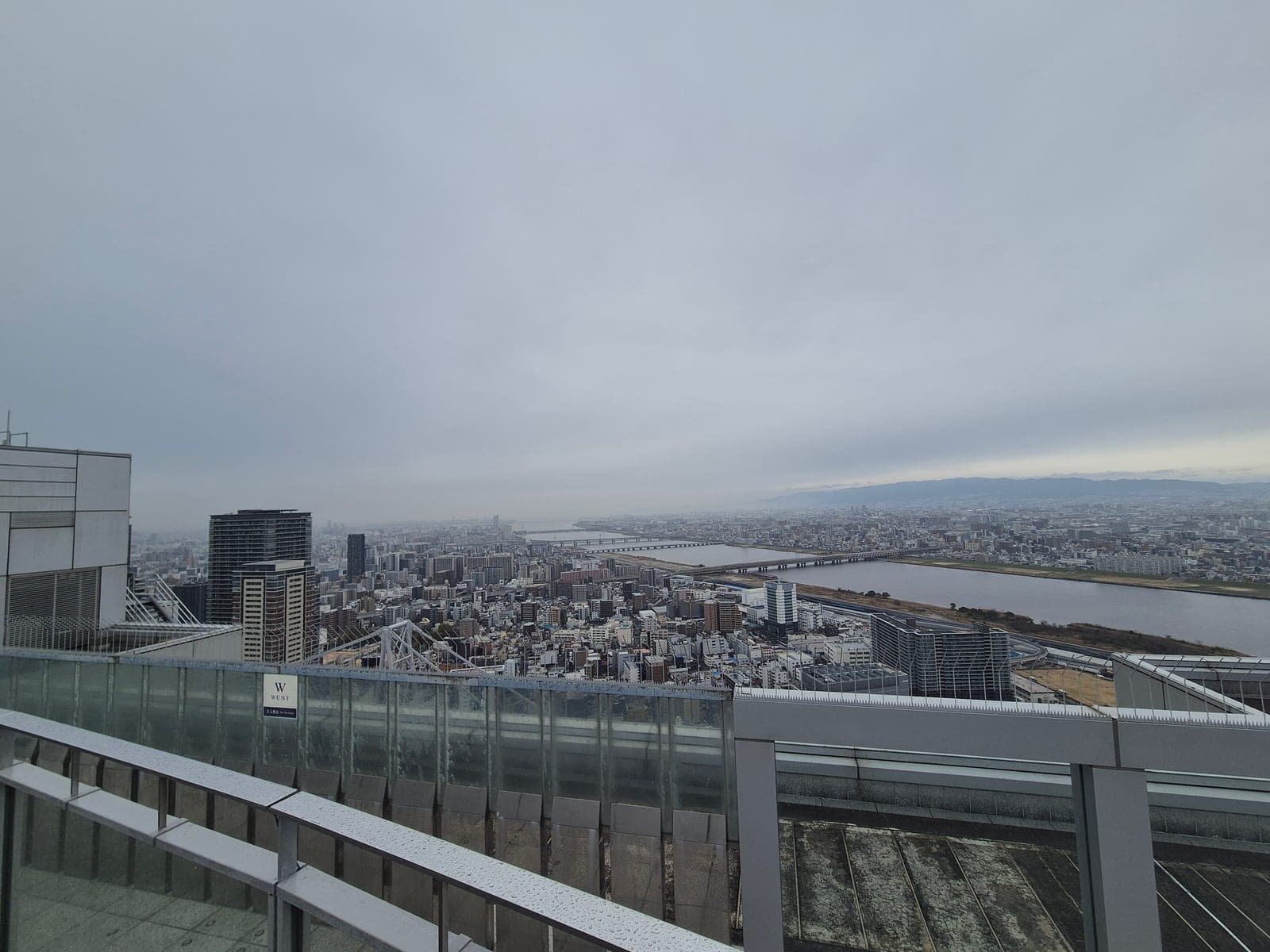 El deck circular del observatorio Kuchu Teien en el Umeda Sky Building, con el río Yodo y sus puentes vistos desde arriba en un día nublado