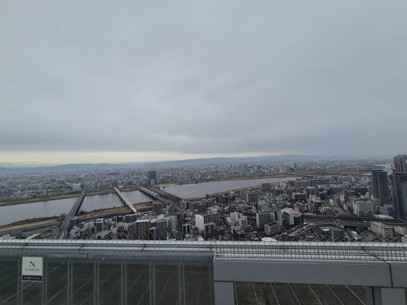 Panorama del denso horizonte de rascacielos de Osaka visto desde el observatorio del Umeda Sky Building, con un helipuerto en primer plano