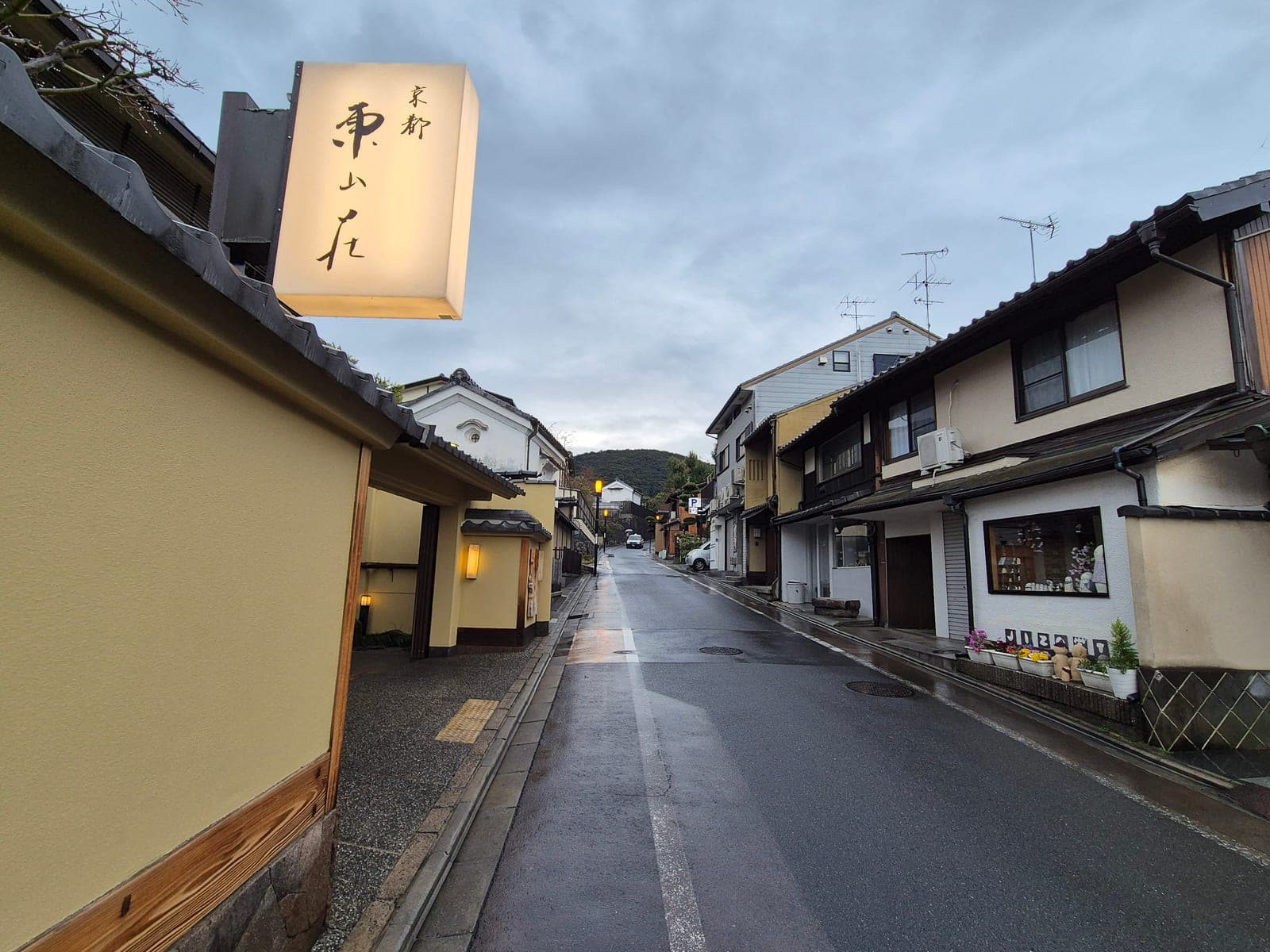 Una calle tradicional de Higashiyama en Kioto casi vacía a primera hora de la mañana, con un letrero iluminado y casas de madera
