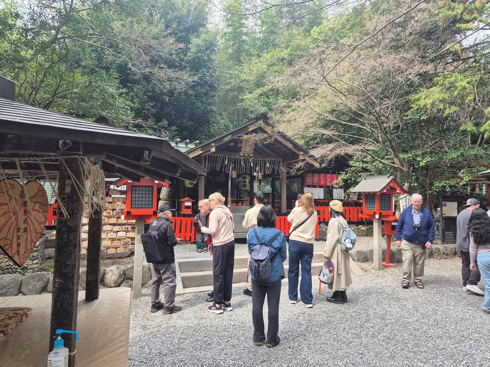 Visitantes reunidos frente al salón principal del santuario Nonomiya, con sus barandales bermellón y el gran ema en forma de corazón a un costado