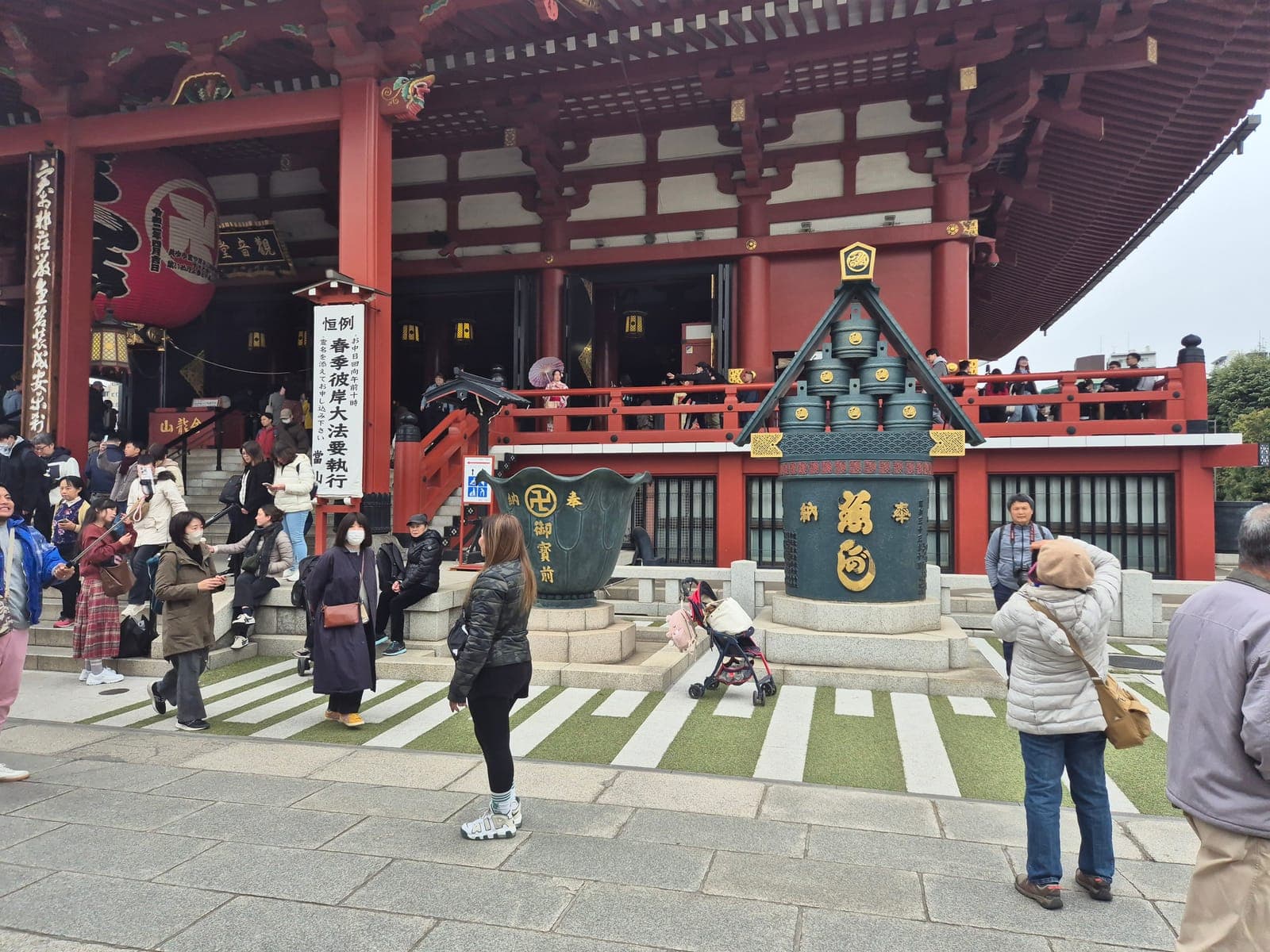 La fachada del salón principal del templo Sensō-ji con su gran farol rojo y visitantes subiendo las escaleras