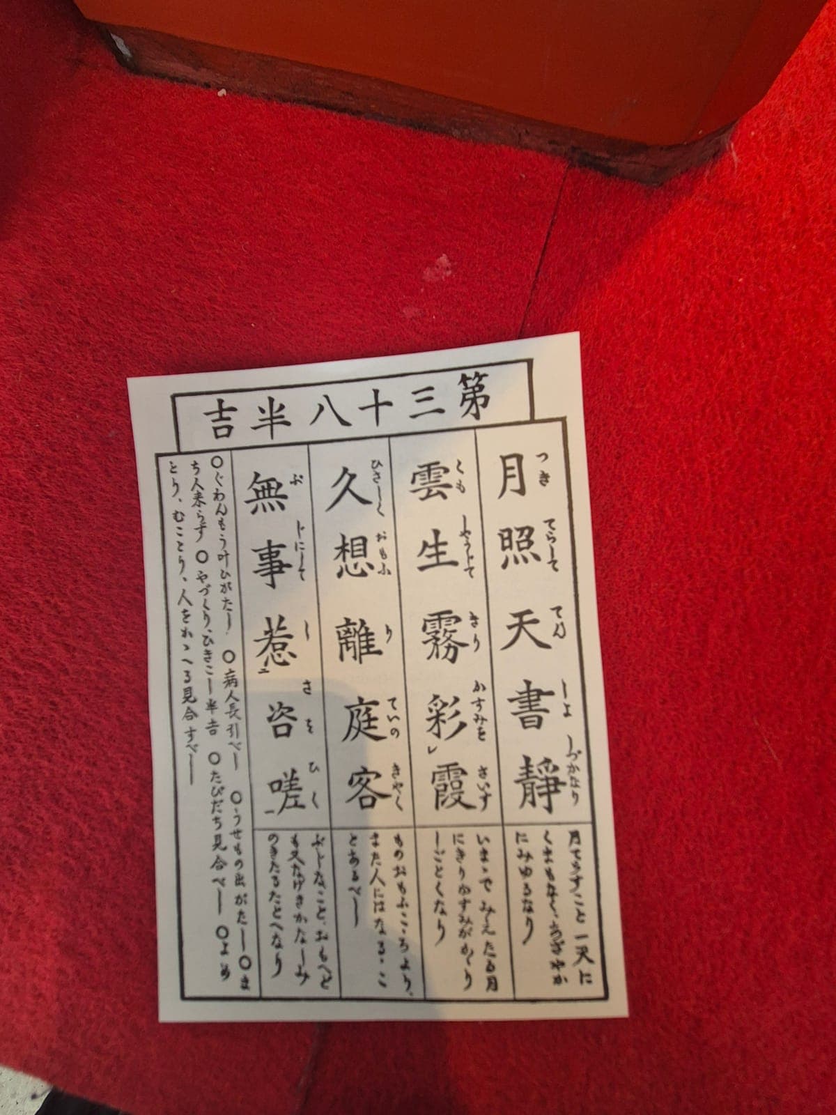 Un papelito omikuji del templo Sensō-ji con caligrafía japonesa, sobre la alfombra roja del puesto de la fortuna