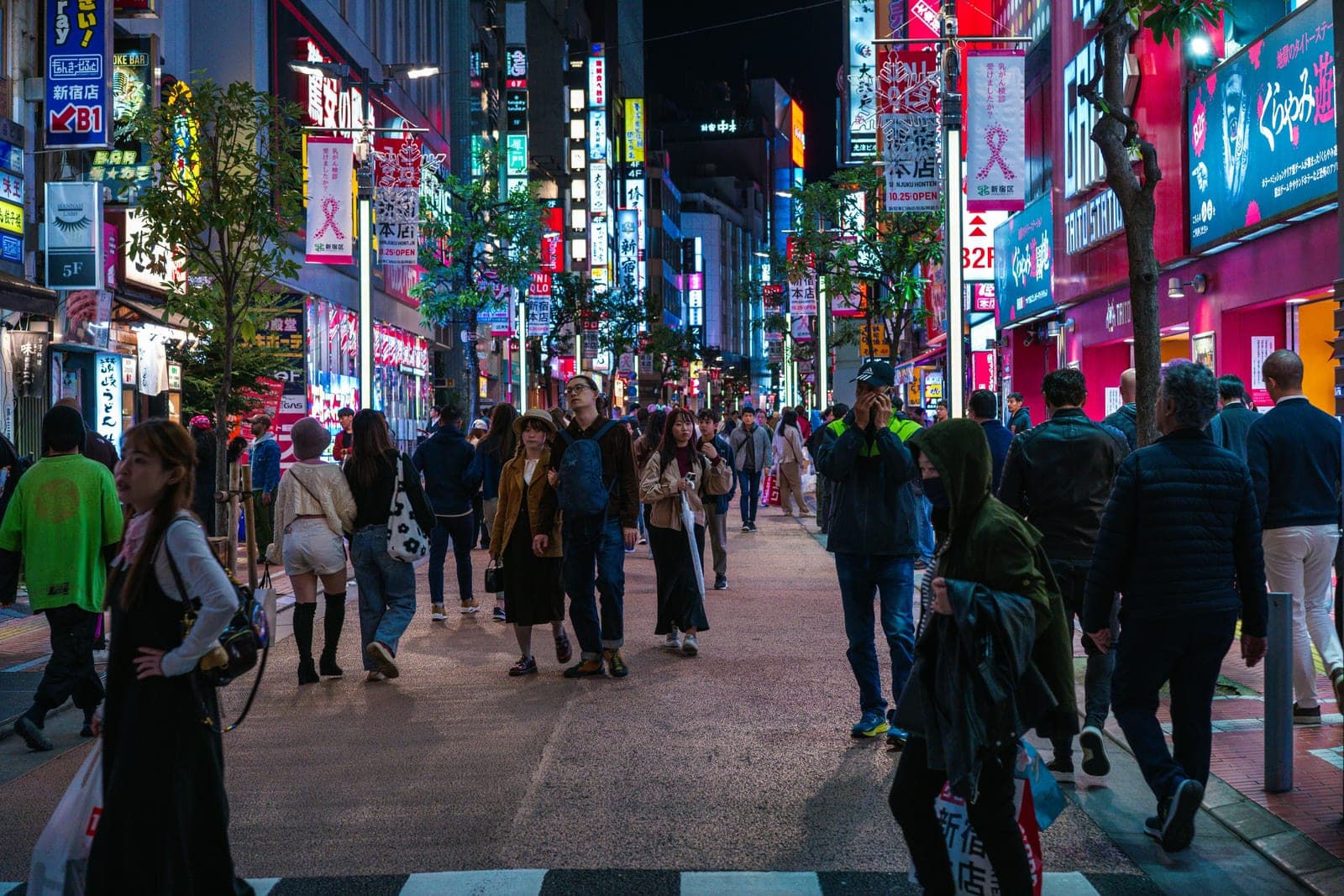 Una calle de Shinjuku de noche, repleta de letreros luminosos y gente caminando entre las tiendas