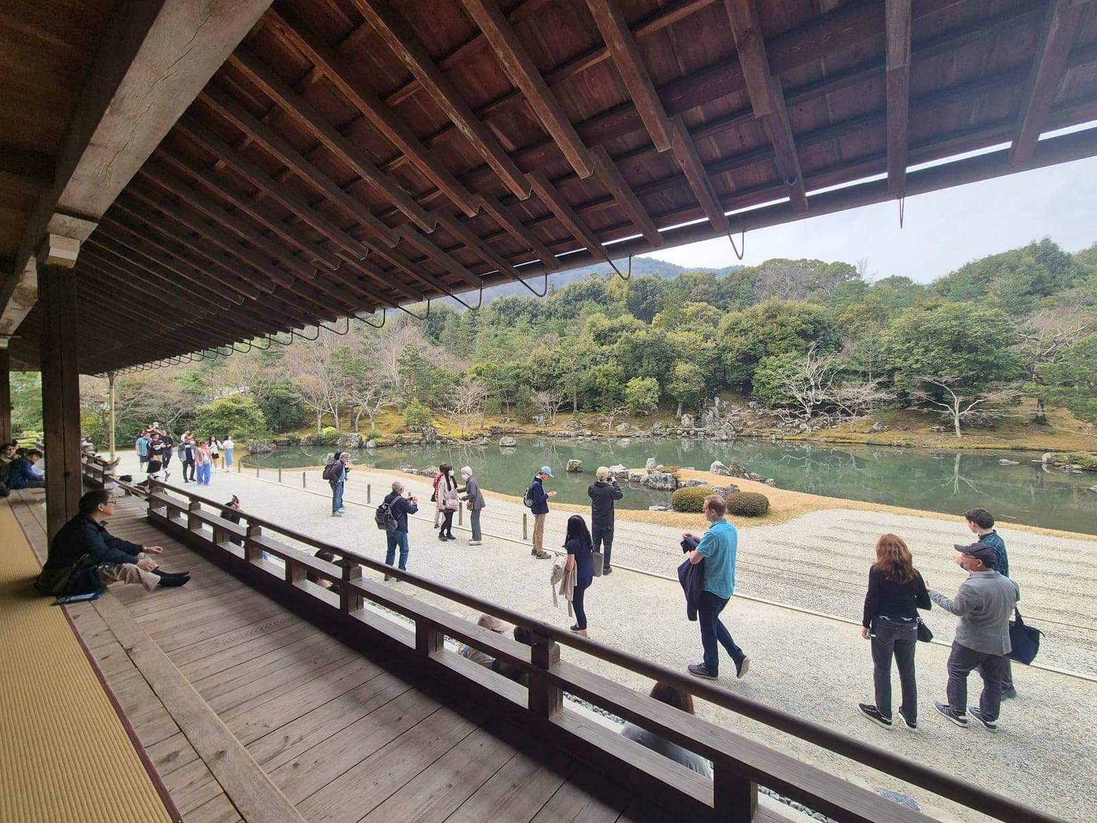 Visitantes en la veranda de madera del templo Tenryū-ji observando el jardín y el estanque Sōgen