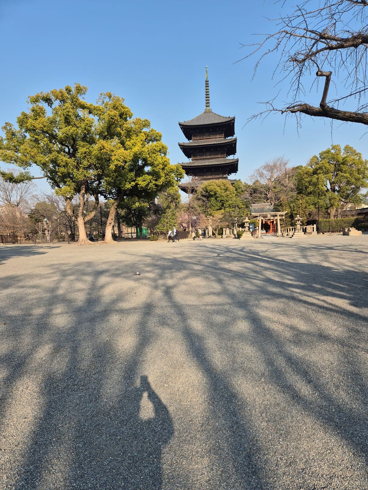La pagoda de cinco pisos del templo Tō-ji vista de cerca, con árboles alrededor y un pequeño santuario con torii rojo a un costado