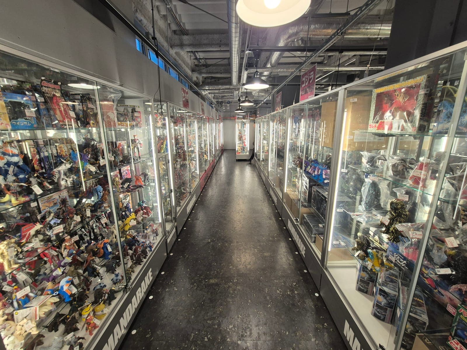 Pasillo de vitrinas iluminadas llenas de figuras de colección vintage en Mandarake Complex de Akihabara