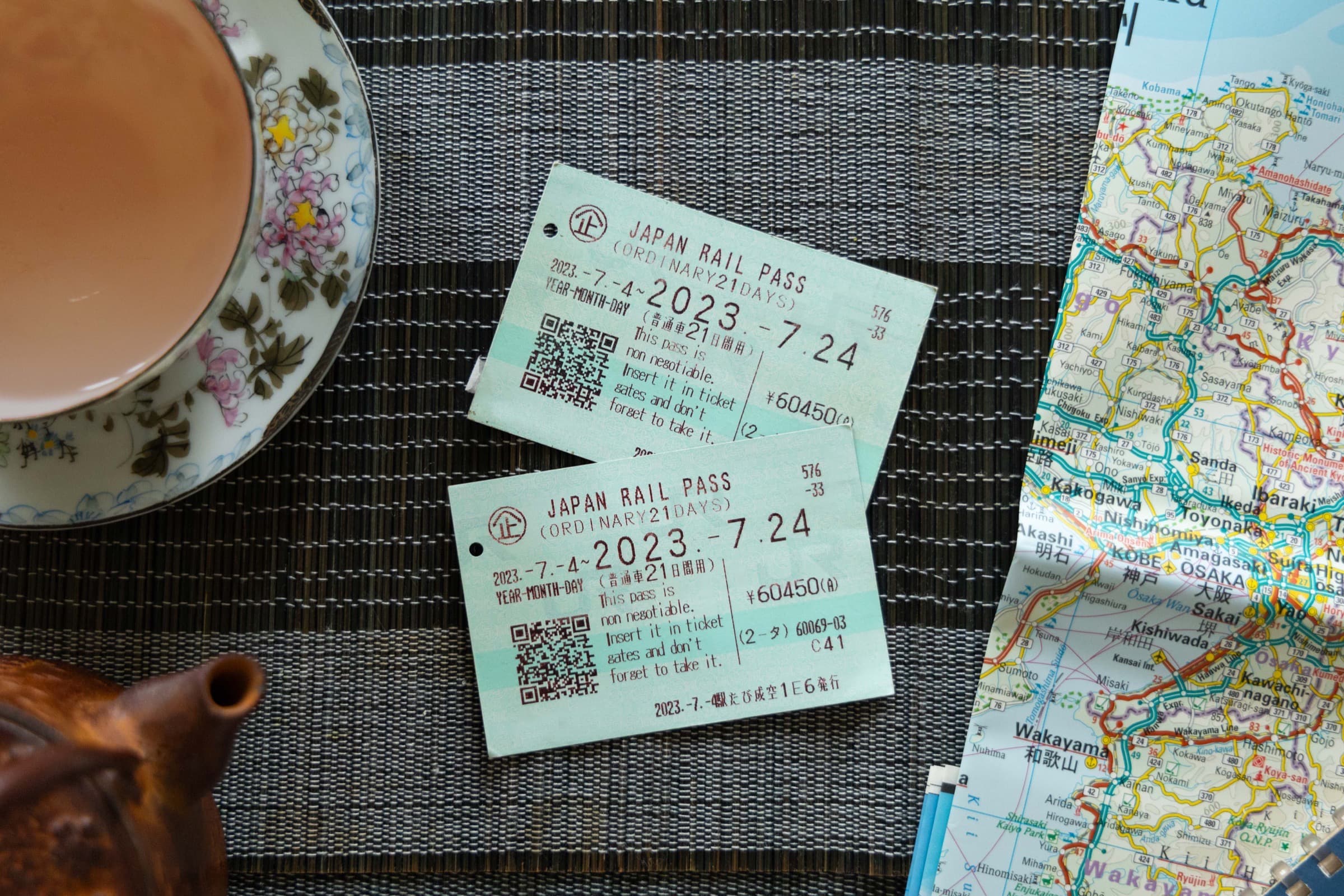 Dos boletos del Japan Rail Pass sobre un mapa de papel, junto a una taza de té