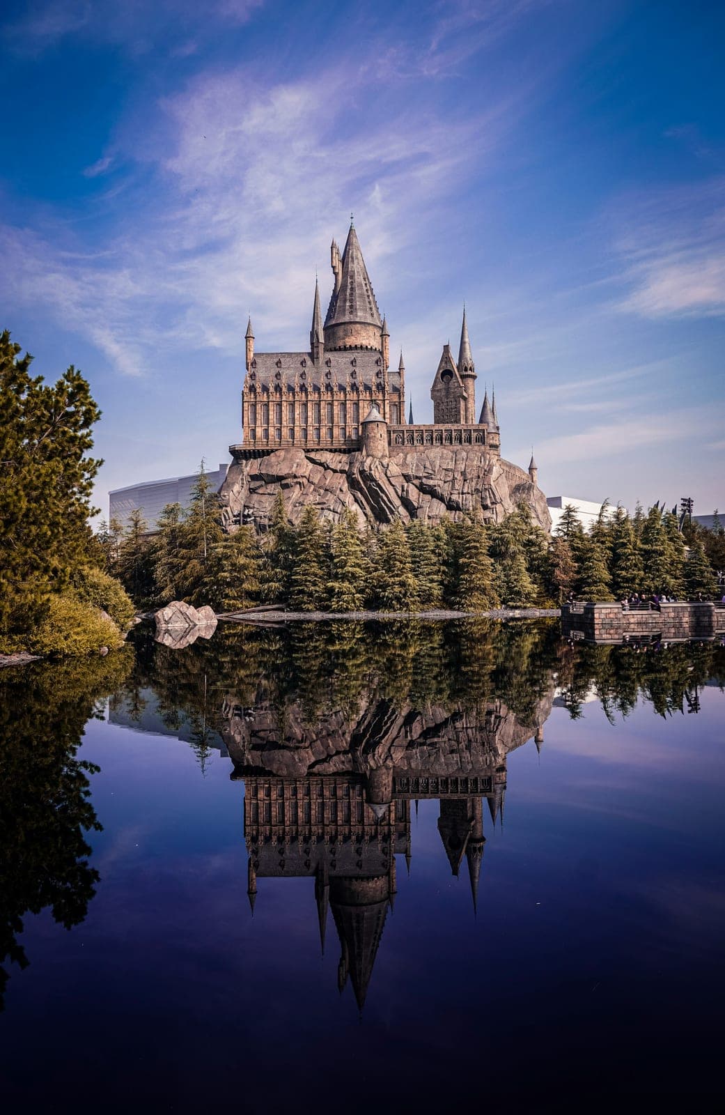 El castillo de Hogwarts de The Wizarding World of Harry Potter en Universal Studios Japan, reflejado en el lago que lo rodea bajo un cielo azul