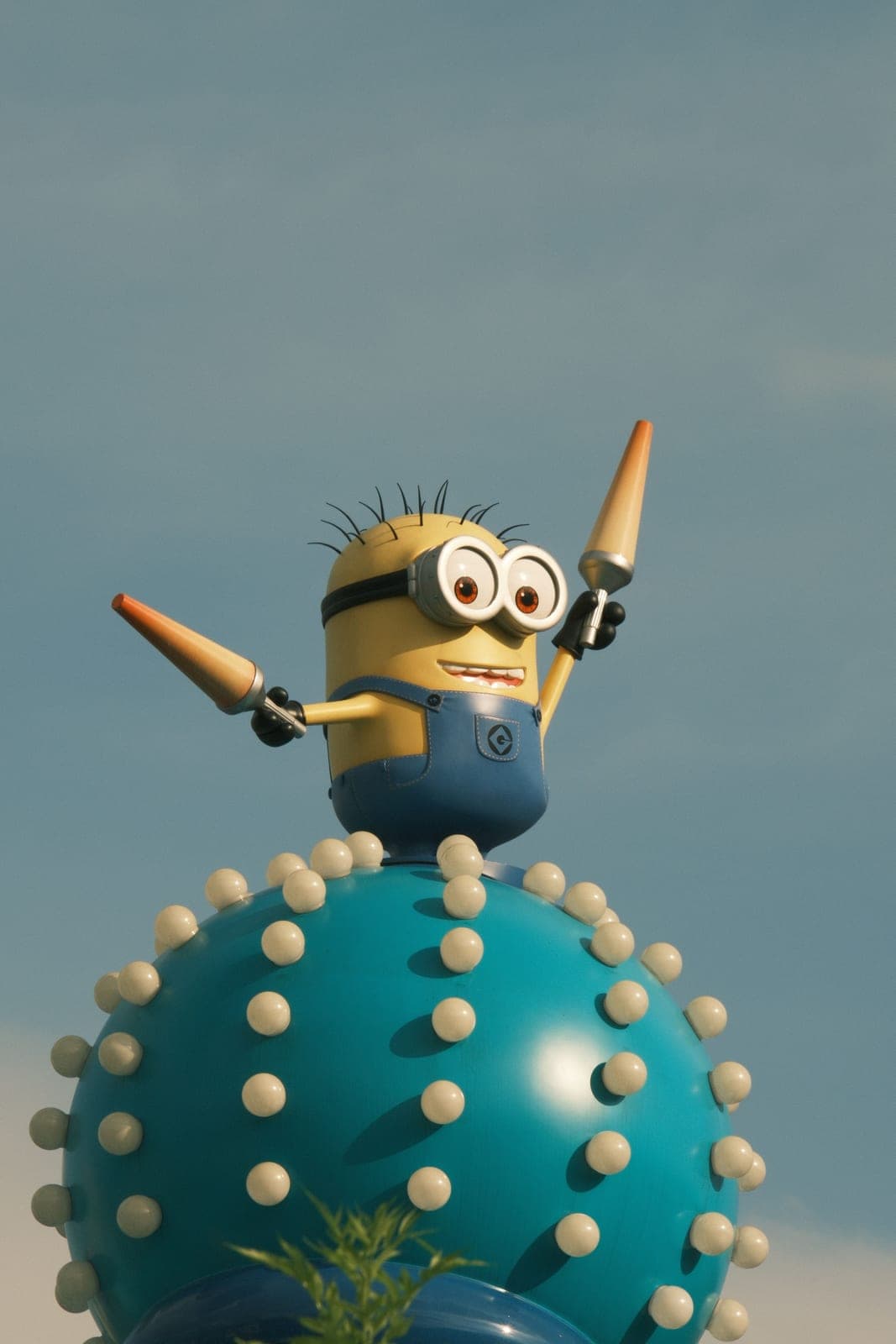 Figura de un Minion con pinos de malabares sobre una esfera azul con picos, una de las decoraciones de Minion Park