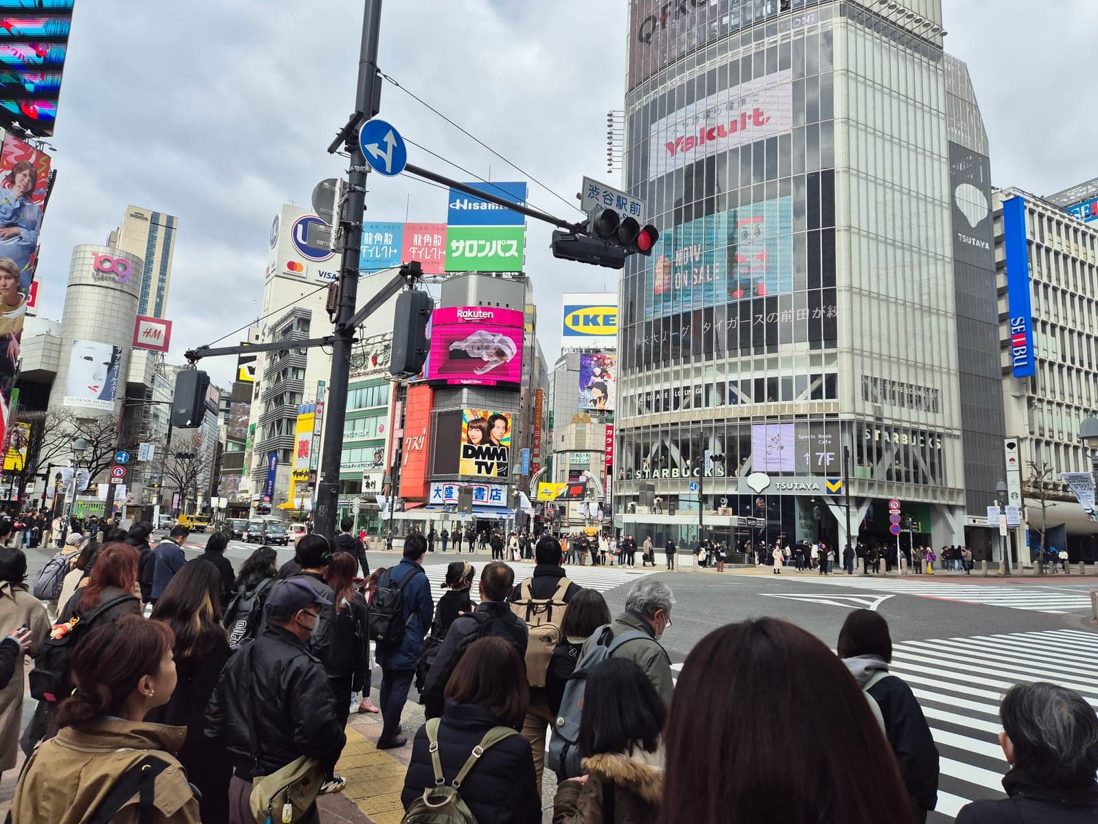 Multitud esperando para cruzar el cruce peatonal de Shibuya en Tokio, frente al edificio Q-Front y la tienda Starbucks de Tsutaya