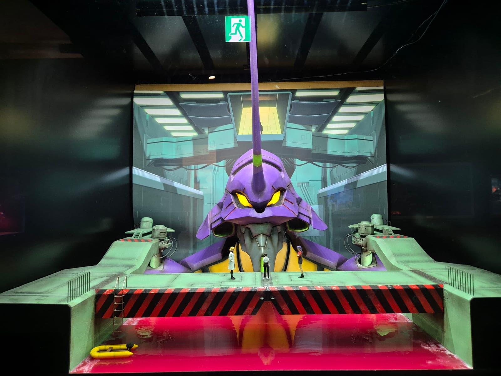 Diorama a escala de la Unidad-01 de Evangelion en su bahía de lanzamiento, con figuras de personajes a escala humana frente a ella, dentro del Museo Kaiyodo en Miraiza Osaka-jo