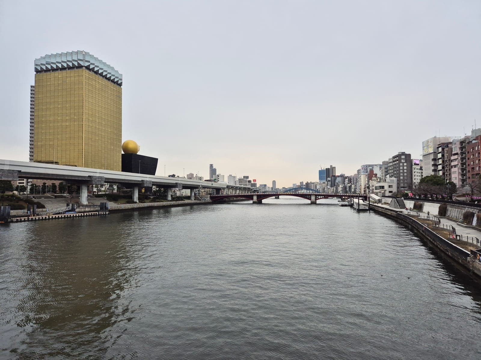 El edificio dorado de Asahi Breweries junto al río Sumida, con su escultura dorada en forma de llama sobre el edificio negro contiguo