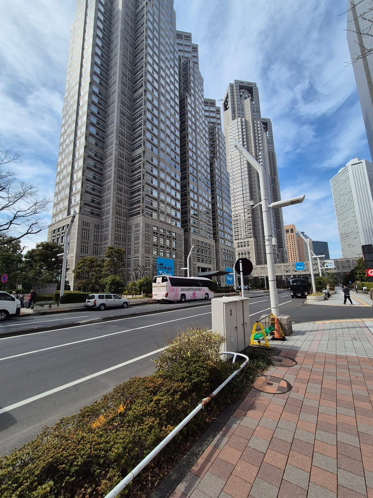 Vista desde abajo del Edificio del Gobierno Metropolitano de Tokio, con sus torres grises elevándose contra un cielo azul con nubes