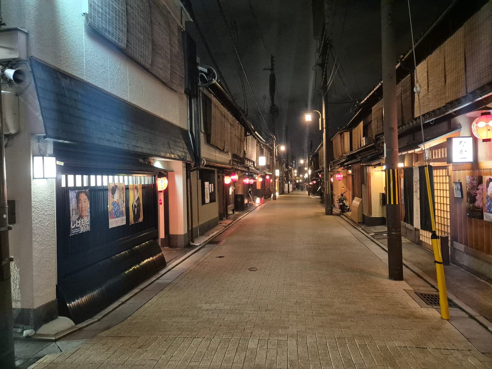 Una calle empedrada del barrio de Gion en Kioto de noche, con farolillos encendidos y casas de té tradicionales de madera