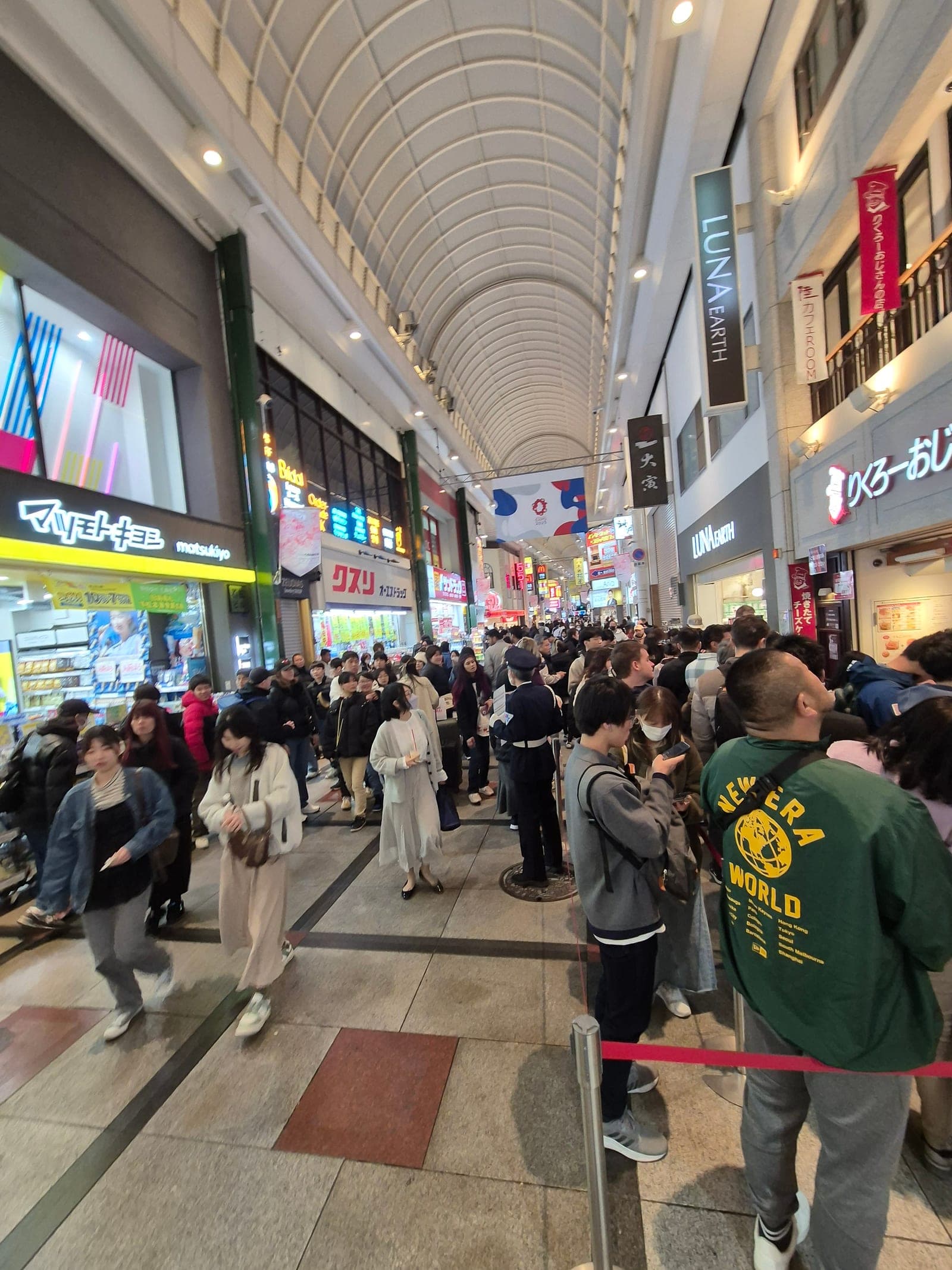 La calle techada de Shinsaibashi-suji en Osaka de noche, llena de gente formada frente a tiendas iluminadas con letreros en japonés