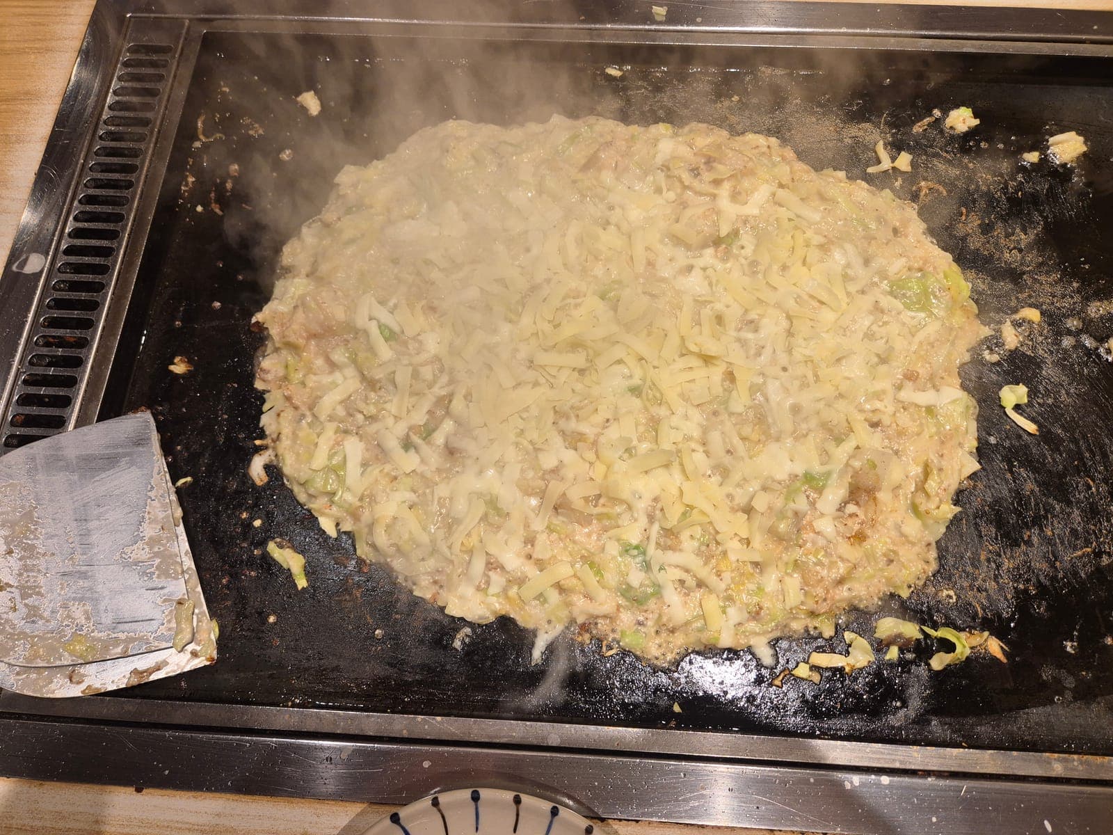 Monjayaki cocinándose sobre una plancha en un restaurante de Asakusa, con queso derretido y col mezclados