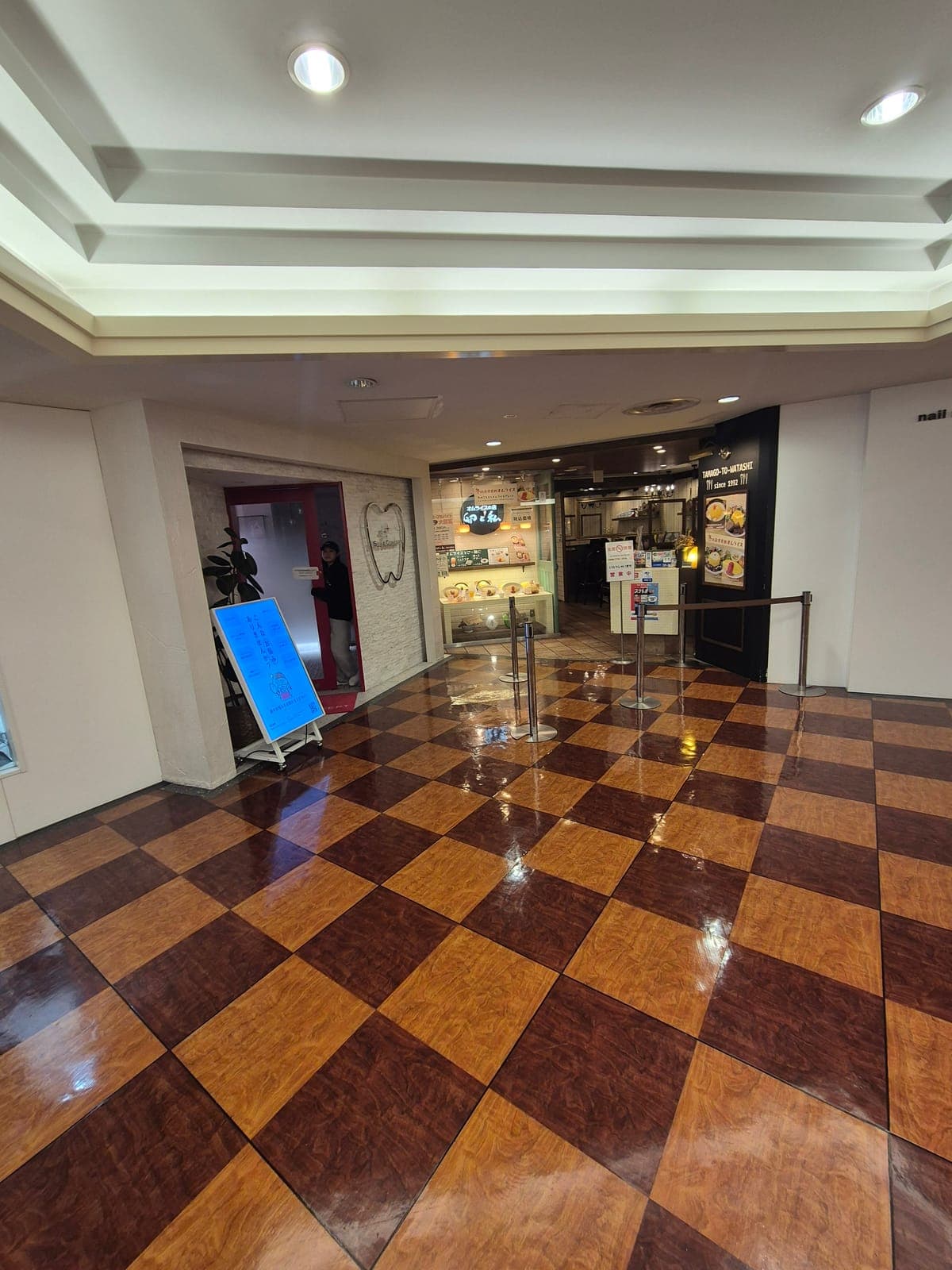 Entrada del restaurante Tamago to Watashi en el pasaje Shibuya Hachibangai, con piso ajedrezado y letrero iluminado