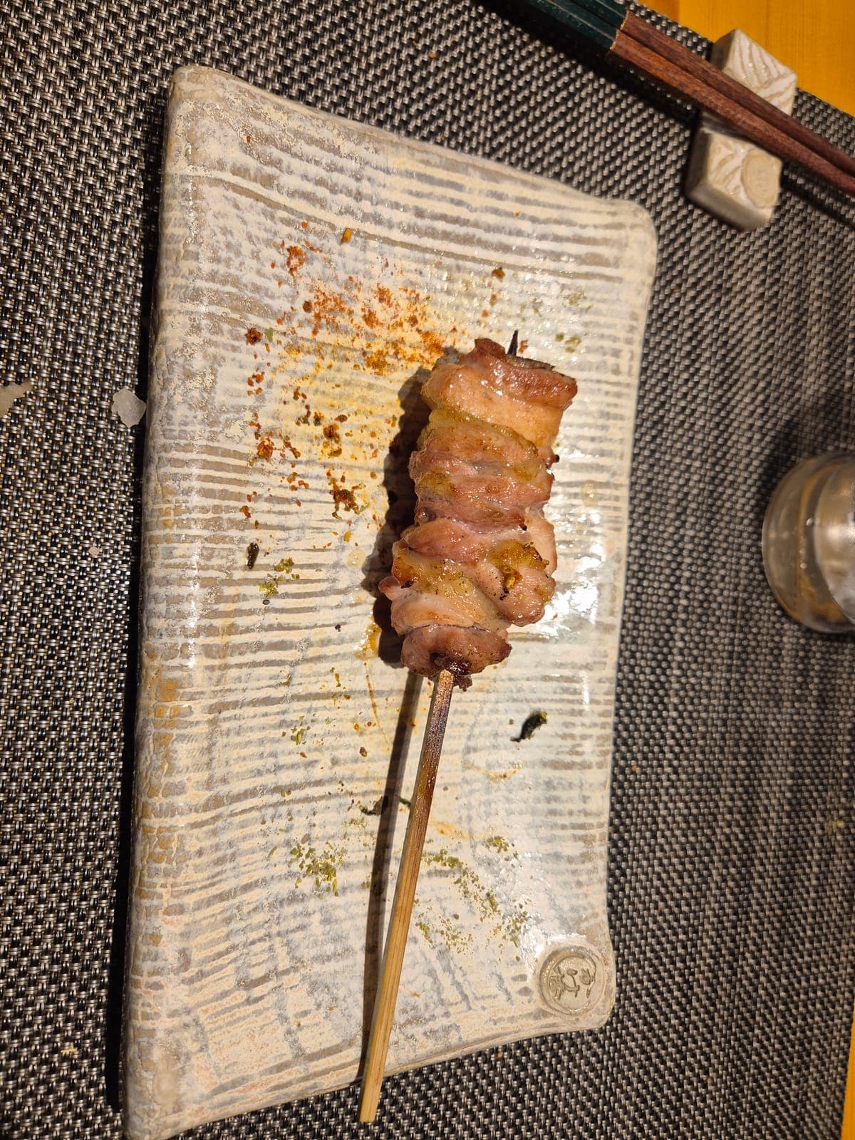 Brocheta de yakitori a la parrilla servida en un plato de cerámica en el restaurante Ueno Kuromon Torie