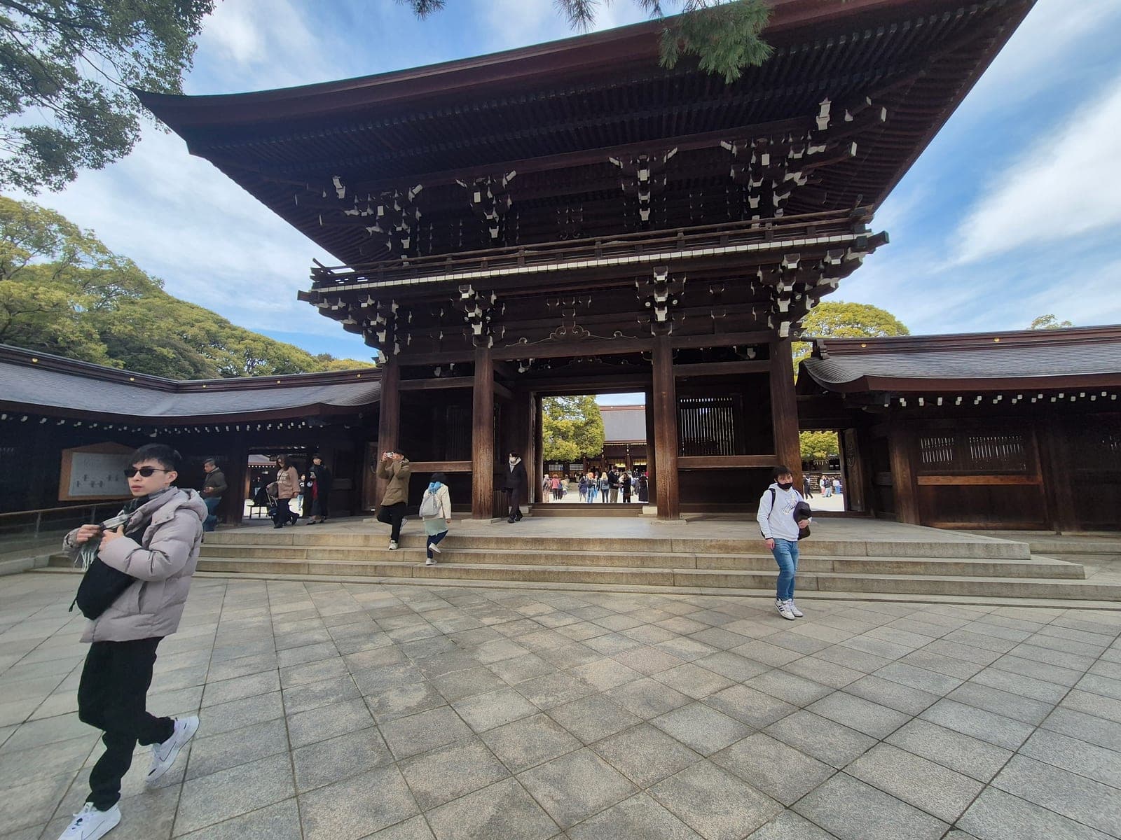 El Kaguraden del santuario Meiji Jingū, un gran pabellón de madera con techo curvo y tiras de papel shide colgando de los aleros, con visitantes cruzando por debajo