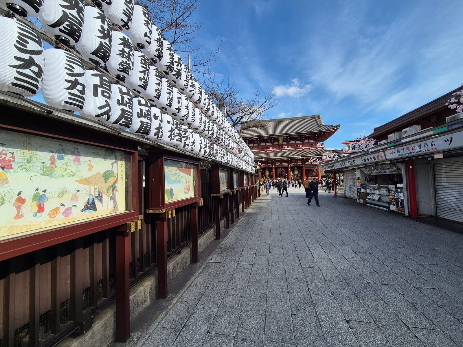 La calle Nakamise del Sensō-ji casi vacía temprano en la mañana, con la puerta Hōzōmon al fondo bajo un cielo azul