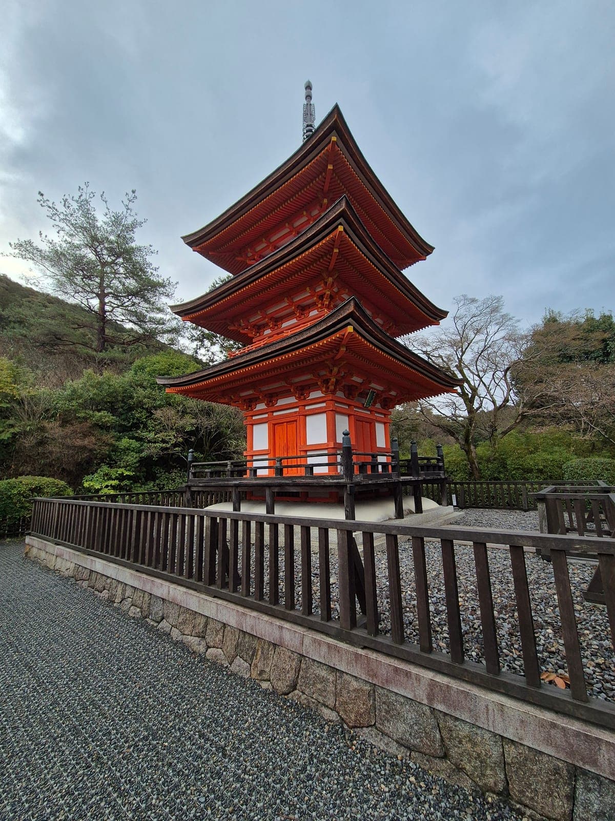 La pagoda de tres pisos de color bermellón del templo Kiyomizu-dera, vista desde el patio principal bajo un cielo nublado
