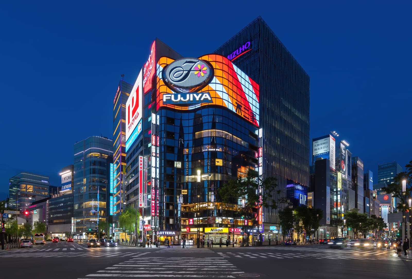 Una esquina de Ginza en Tokio a la hora azul, con las fachadas iluminadas de los edificios y el cruce peatonal