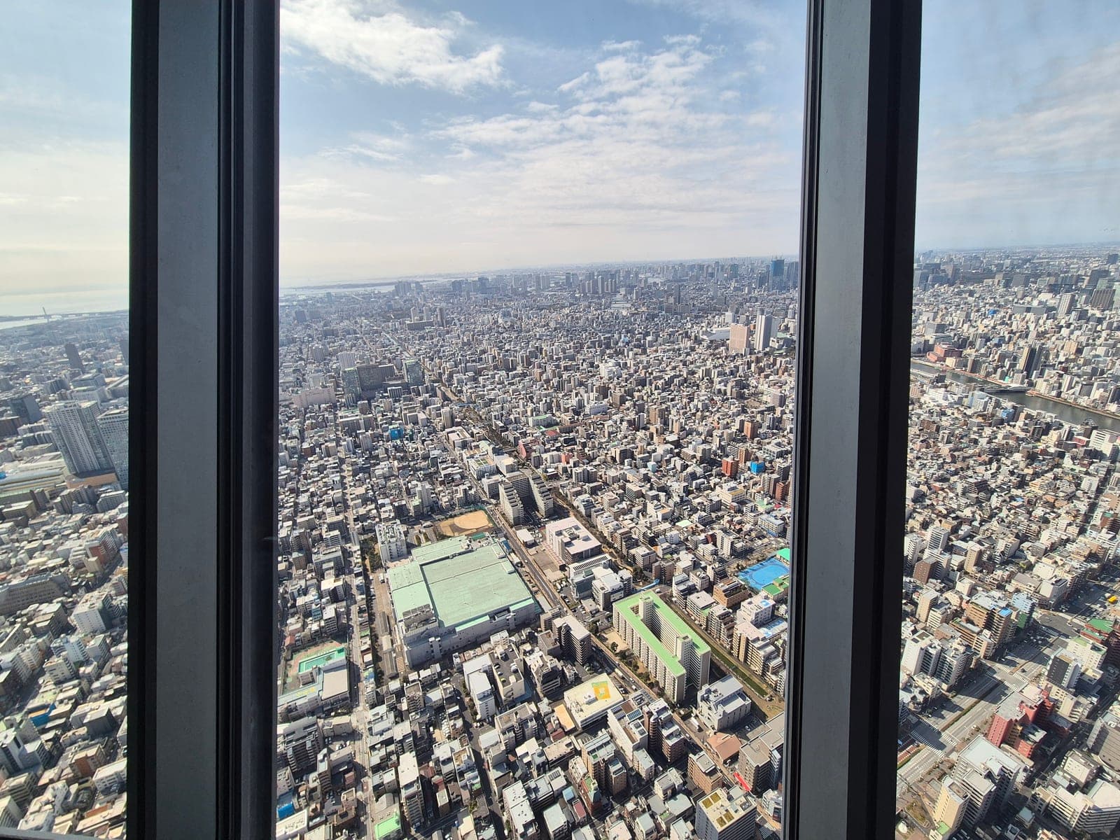 Vista de la ciudad de Tokio a través de los ventanales del Tembo Deck de Tokyo Skytree, con el paisaje urbano extendiéndose hasta el horizonte