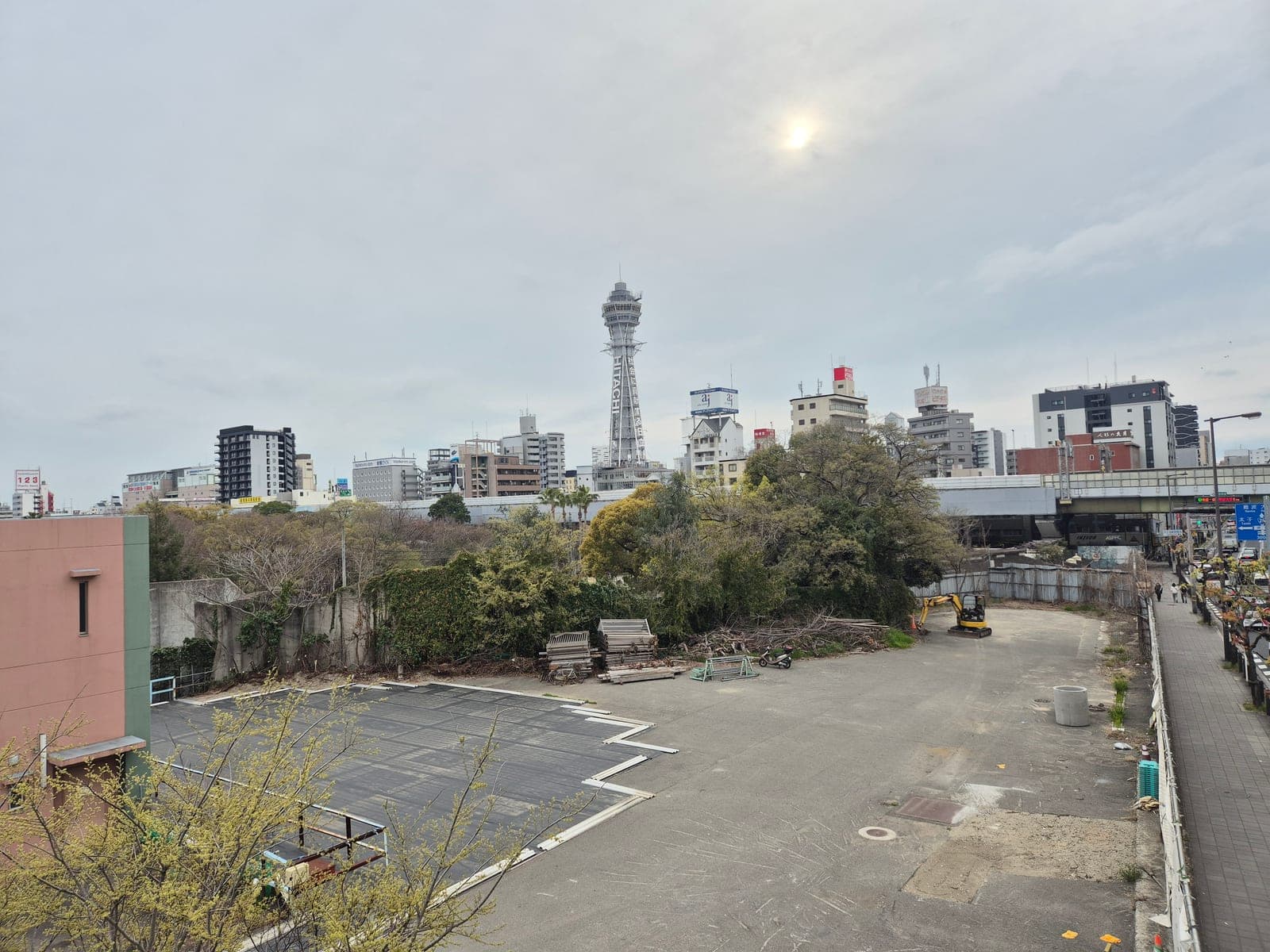 La torre Tsutenkaku vista desde lejos entre los edificios de Shinsekai en Osaka, bajo un cielo nublado