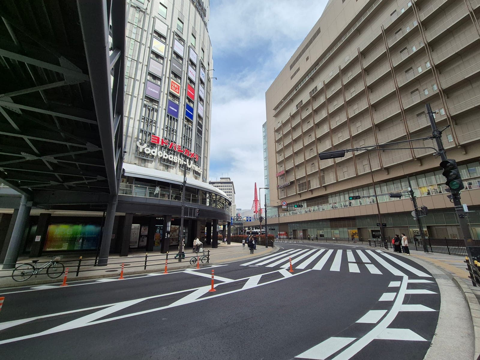 La fachada de la tienda de electrónica Yodobashi Umeda con su letrero rojo, junto a un cruce peatonal en Osaka